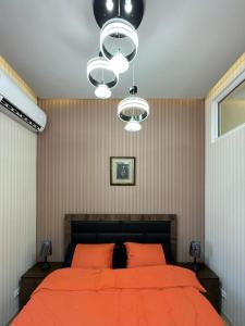 a bedroom with a bed with orange sheets and a chandelier at Dushanbe City View Apartments in Dushanbe