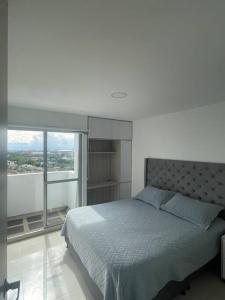 um quarto com uma cama e uma grande janela em Altavista Apartamento Lindo y Comodo Piso 8 en Pereira em Pereira