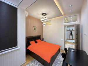a bedroom with a bed with orange sheets and a table at Dushanbe City View Apartments in Dushanbe