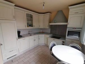 una cocina con armarios blancos y una mesa. en Huis Rochelle, en Bredene