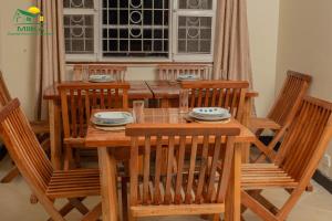 a wooden dining room table with four chairs and a table and chairsuggest at Miika Guest House in Entebbe