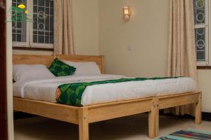 1 cama con marco de madera en un dormitorio en Miika Guest House en Entebbe