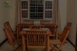 a dining room with a wooden table and chairs at Miika Guest House in Entebbe