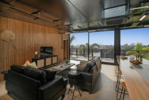 a living room with leather furniture and a large window at Panorama Vista in Pauanui