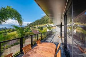 a deck with a wooden table and chairs on a balcony at Panorama Vista in Pauanui