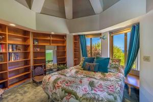 een slaapkamer met een bed en boekenplanken bij Opulent Waterfall House with Ocean Views in Haiku, Maui in Huelo
