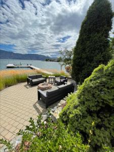 a patio with two couches and a firepit next to the water at Lake House at Quails' Gate Winery in West Kelowna