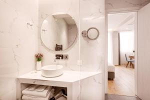 uma casa de banho branca com um lavatório e um espelho em DAYS City Suites Athens em Atenas