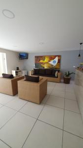 a living room with couches and a tv on the wall at Pousada Pedras do Porto in Porto De Galinhas