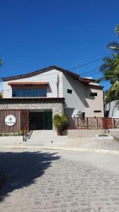 a white house with a fence in front of it at Pousada Pedras do Porto in Porto De Galinhas