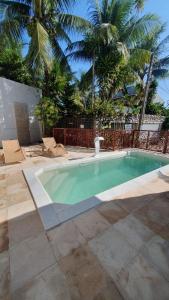 a swimming pool in a yard with palm trees at Pousada Pedras do Porto in Porto De Galinhas