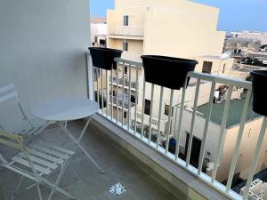 balkon z krzesłami i widokiem na budynek w obiekcie Sunnyside Penthouse w mieście Tarxien