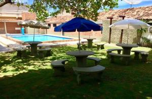 a group of picnic tables and umbrellas next to a pool at Chalé em Tamandaré in Tamandaré