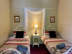 two twin beds in a room with a window at Barnard street Cottage in Bendigo