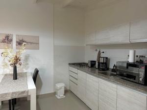 a kitchen with white cabinets and a table with a vase of flowers at Apartamento de las Araucarias in Esquel
