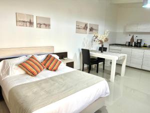 a bedroom with a bed and a table and a kitchen at Apartamento de las Araucarias in Esquel