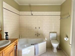 a bathroom with a tub and a toilet and a sink at Barnard street Cottage in Bendigo