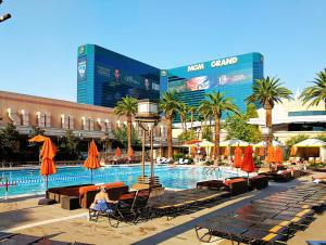 a woman sitting in chairs next to a swimming pool at Strip view 1 BR suite 2 Full Bath Full Kitchen with Balcony - 900 sqft - MGM Signature in Las Vegas