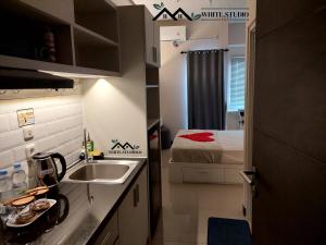a small kitchen with a sink and a bed at White Studio Group Surabaya - WS 821 at Amega Crown Residence in Tambakoso