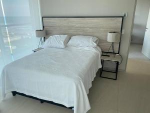 a bedroom with a large white bed and two lamps at Increíble Depa en la mejor zona de Acapulco. in Aguacatillo