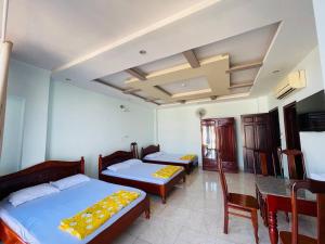 a bedroom with two beds and a table and chairs at Manh Hung Hotel in Buon Ma Thuot