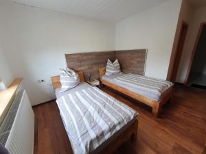 two beds in a room with wooden floors at Hotel Restaurant TAPASTA in Neuwied