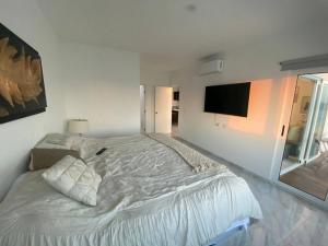 a white bedroom with a large bed and a flat screen tv at Lovely 2 bedroom oceanfront condo in Mazatlan in Mazatlán +23 photos