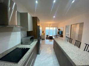 a kitchen with a counter top and a living room at Lovely 2 bedroom oceanfront condo in Mazatlan in Mazatlán