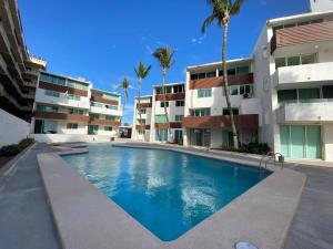 a swimming pool in front of a building with palm trees at Lovely 2 bedroom oceanfront condo in Mazatlan in Mazatlán
