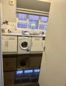 a kitchen with a washing machine and a window at Cosy Room by Excel, Emirates Cable Car, 02Arena in London