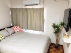 sypialnia z białym łóżkiem i oknem w obiekcie Nishikujo stay5 - Vacation STAY 14800 w Osace