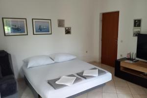 a bedroom with a white bed and a television at Apartments by the sea Postira, Brac - 9241 in Postira