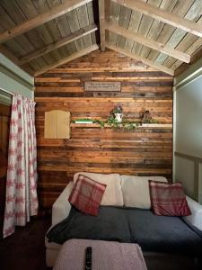 a bed in a room with a wooden wall at Maple tree lodge. Quirky handcrafted Irish cabin in Dromara