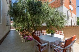 a table and chairs on a patio with a tree at Apartments with a parking space Tar, Porec - 6948 in Tar
