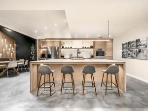 a kitchen with a large island with four bar stools at 1_OAK - experience custom design - 2 masters in Houston