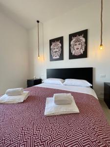 una camera da letto con un grande letto con due asciugamani di {Palazzo Fodale-5 stelle} APARTMENT 70’s ROOMS a Trapani