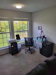 a living room with a desk and a chair and two windows at Serenity Apartment in Chesterfield
