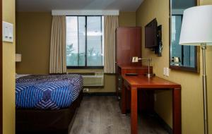 クイーンズにあるSky Hotel Flushing/Laguardia Airportのベッド、デスク、窓が備わるホテルルームです。