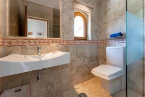 a bathroom with a toilet and a sink and a mirror at The Quinta - 3 Bedroom ensuite Villa, Swimming Pool, Beautiful Gardens, water features and lake in Almancil +30 photos