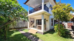 a white house with a balcony and a yard at Bali Fab Dive Center in Amed