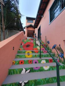 un conjunto de escaleras con flores pintadas en ellas en Villa Ida Acomodações, 3 suítes aconchegantes e charmosas no centro en Serra Negra