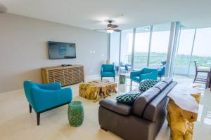 a living room with a couch and blue chairs at 23o Penthouse Stunning Oceanview Resort Lifestyle in ArraijÃ¡n