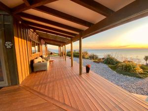 a porch of a house with a view of the ocean at Wild Weka Eco Stay - Off-Grid 4WD RECOMMENDED in Waimarie