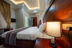 a bedroom with a bed and a lamp on a table at Las Vegas Garden Hotel Mbarara in Mbarara