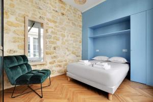 a bedroom with a white bed and a green chair at Very nice triplex apartment bright in Montorgueil in Paris