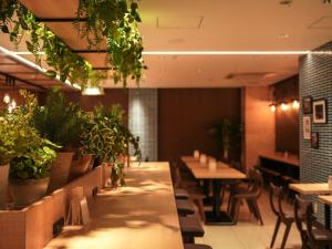 a restaurant with tables and chairs and potted plants at Super Hotel Hiroshima in Hiroshima