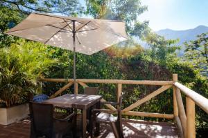 une table et des chaises avec un parasol sur une terrasse dans l'établissement Minka Paradise, à Minca