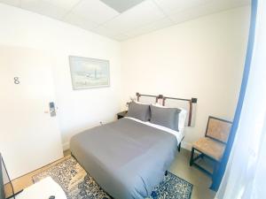 a white bedroom with a bed and a chair at ITH Santa Barbara Beach Hostel in Santa Barbara