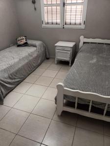 een slaapkamer met 2 bedden en een tegelvloer bij Casa amplia en Resistencia in Resistencia