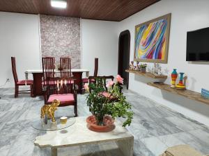 Guarajuba Sereia House في غوارايوبه: غرفة معيشة مع طاولة وكراسي ولوحة